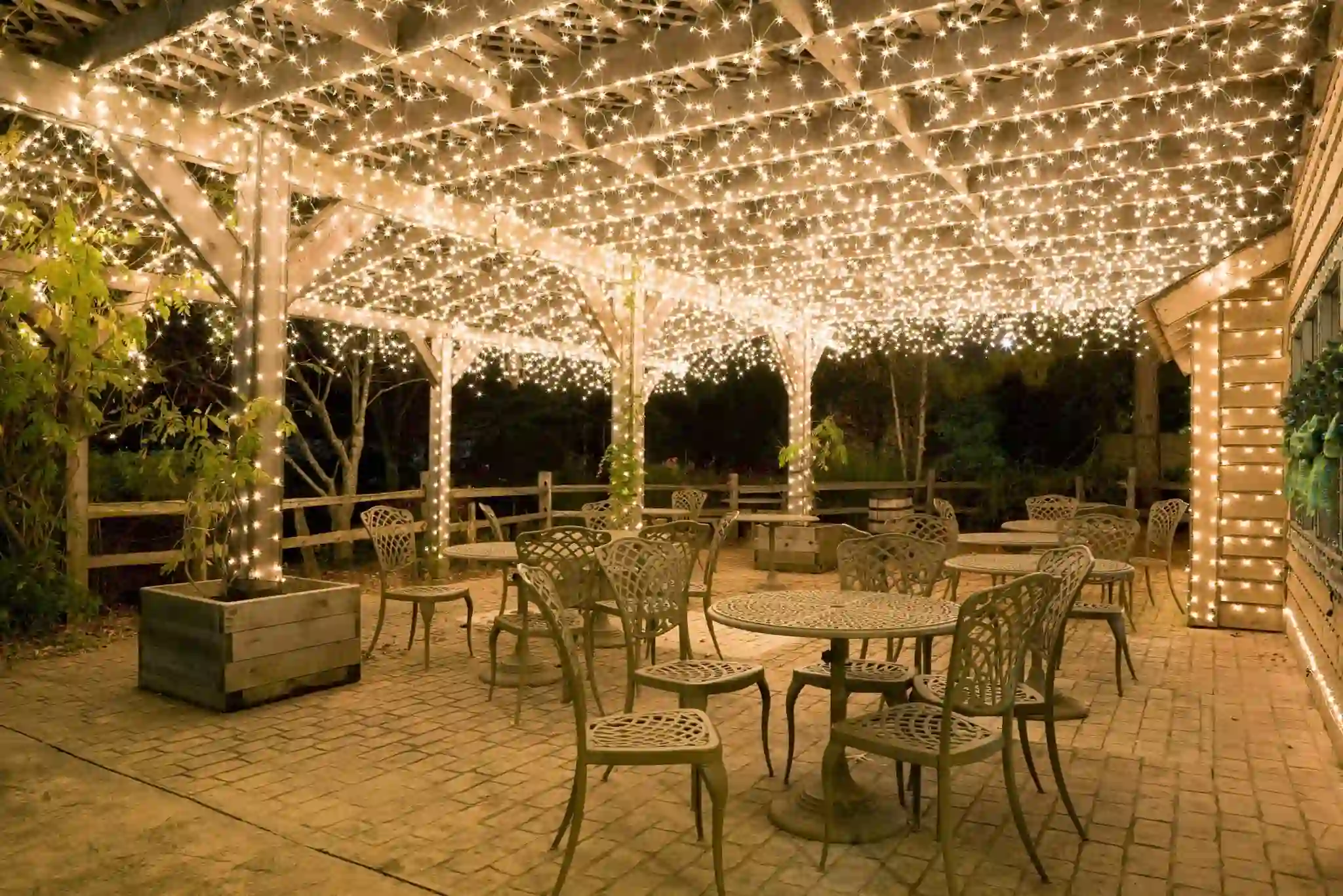 Are string lights best for patio lights — warm white LED fairy lights covering a wooden pergola over an outdoor patio dining area